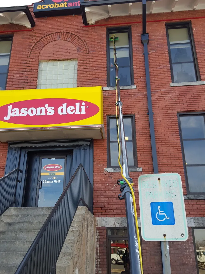 A water-fed pole on the upper windows of a brick storefront building.