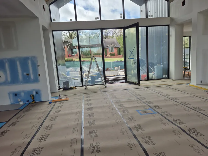 Tall glass doors and clerestory windows in a new home, with one door open to the pool.