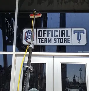 A water-fed pole cleaning the glass above the team store doors at ONEOK Field.
