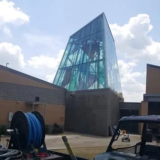 A slanted glass tower on a brick building, with a hose reel on the work truck in front.
