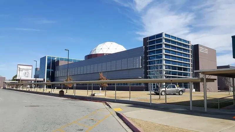 A long office building with rows of windows, seen across a parking lot.