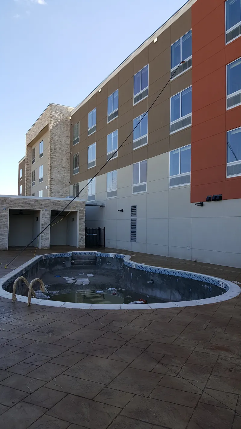 A four-story hotel behind an empty outdoor pool.