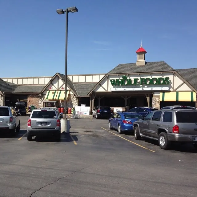 The covered front entrance of a grocery store, with a full parking lot.