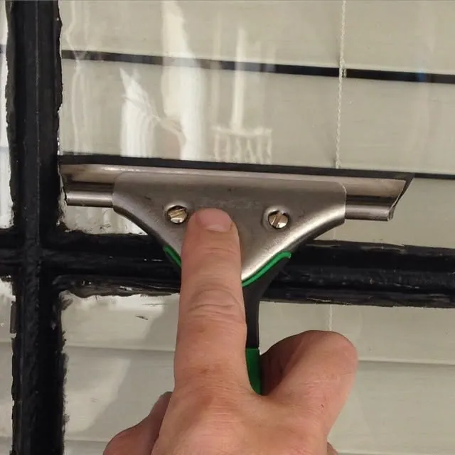 A squeegee pulling water off a pane of glass.