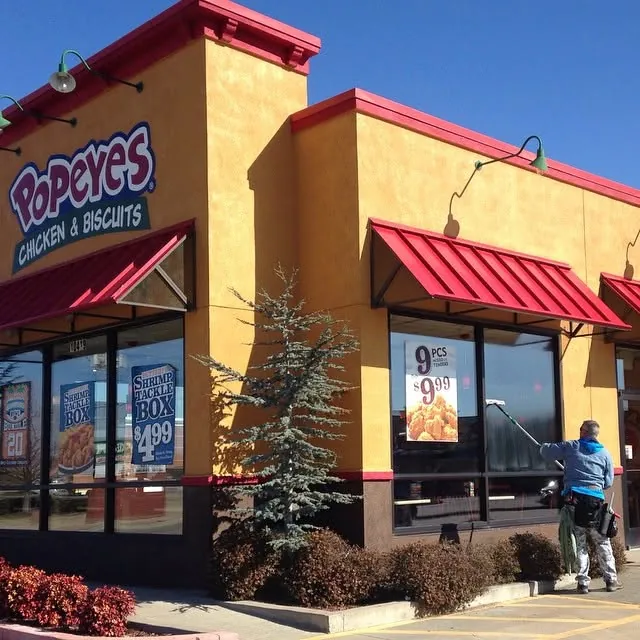 A window cleaner using a pole on the front windows of a restaurant.