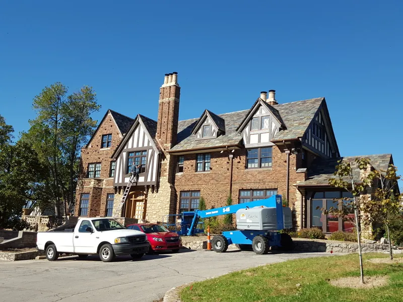 A large historic brick and stone home with steep gables and tall chimneys.