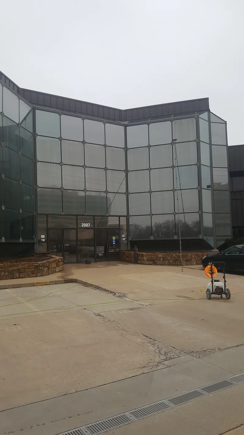 A tall curtain wall of glass on an office building, with a pure-water cart in the parking lot.