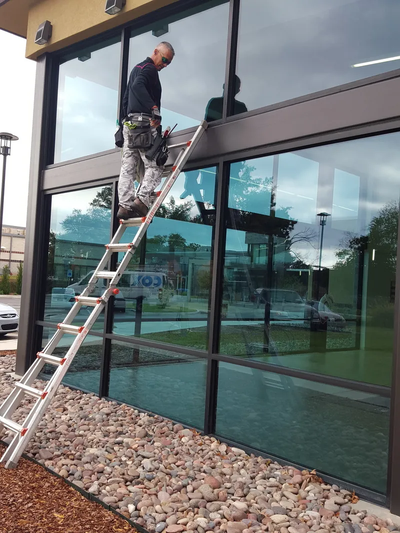 A window cleaner on a ladder cleaning the glass front of a store.